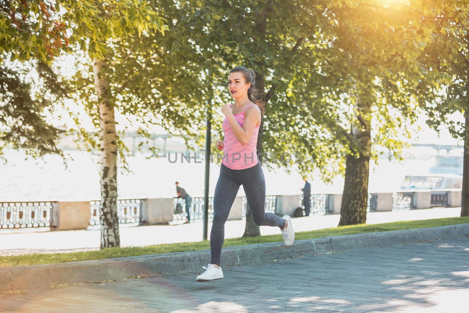 Pretty sporty woman jogging at park in sunrise light at morning