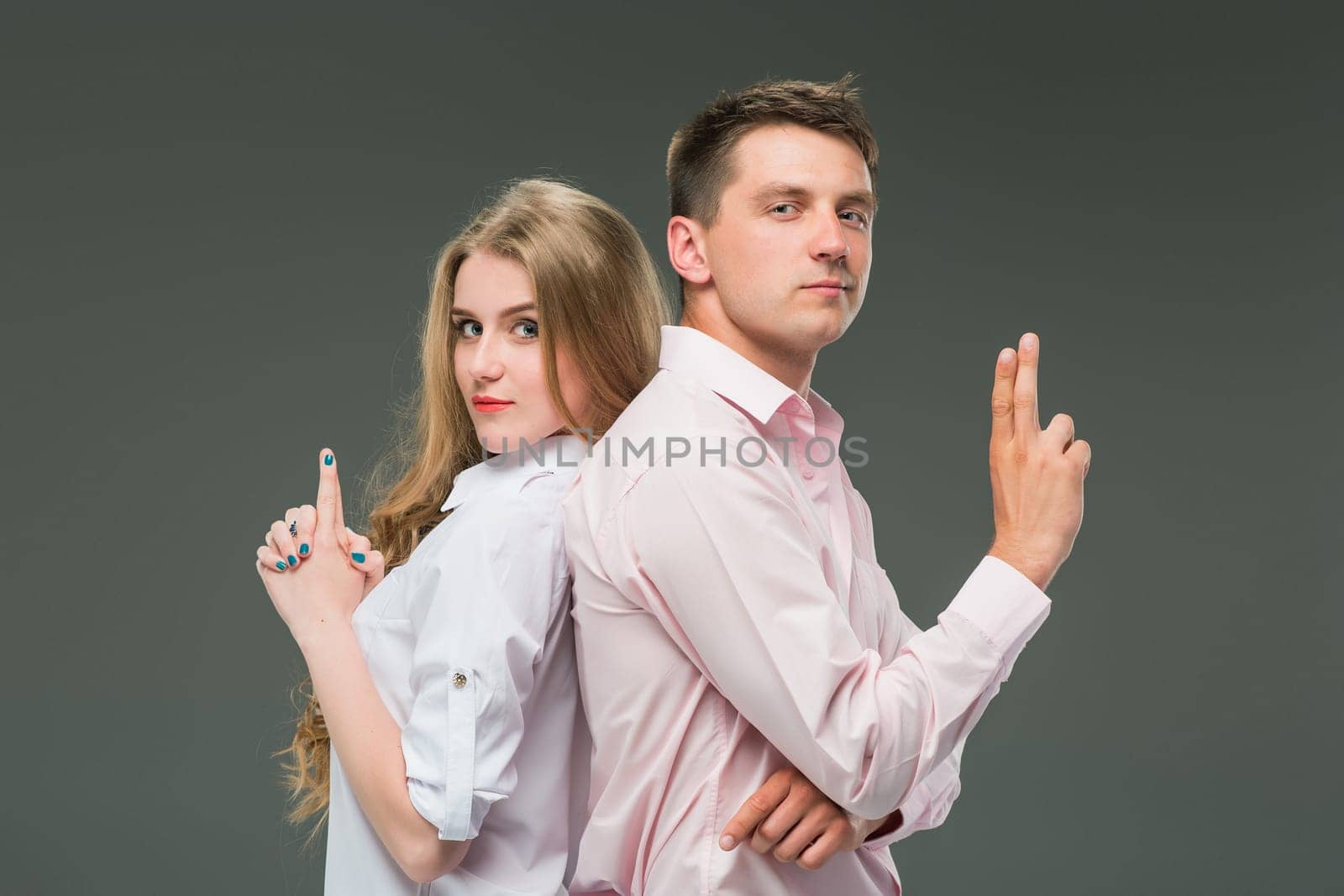 The young couple with different emotions during conflict on gray background