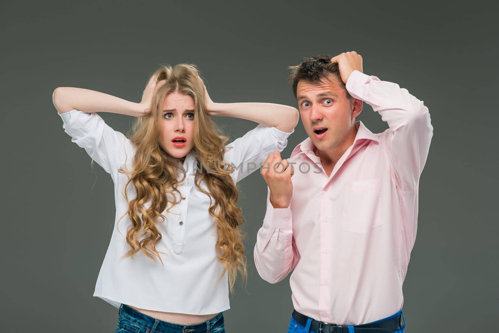 The young couple with different emotions during conflict on gray background