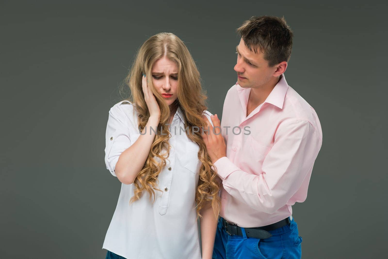 The young couple with different emotions during conflict on gray background