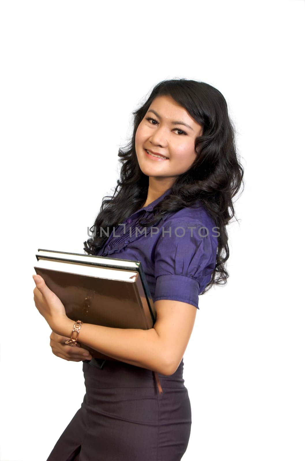 Beautiful college student holding book in her hand. She looks happy and intelligent