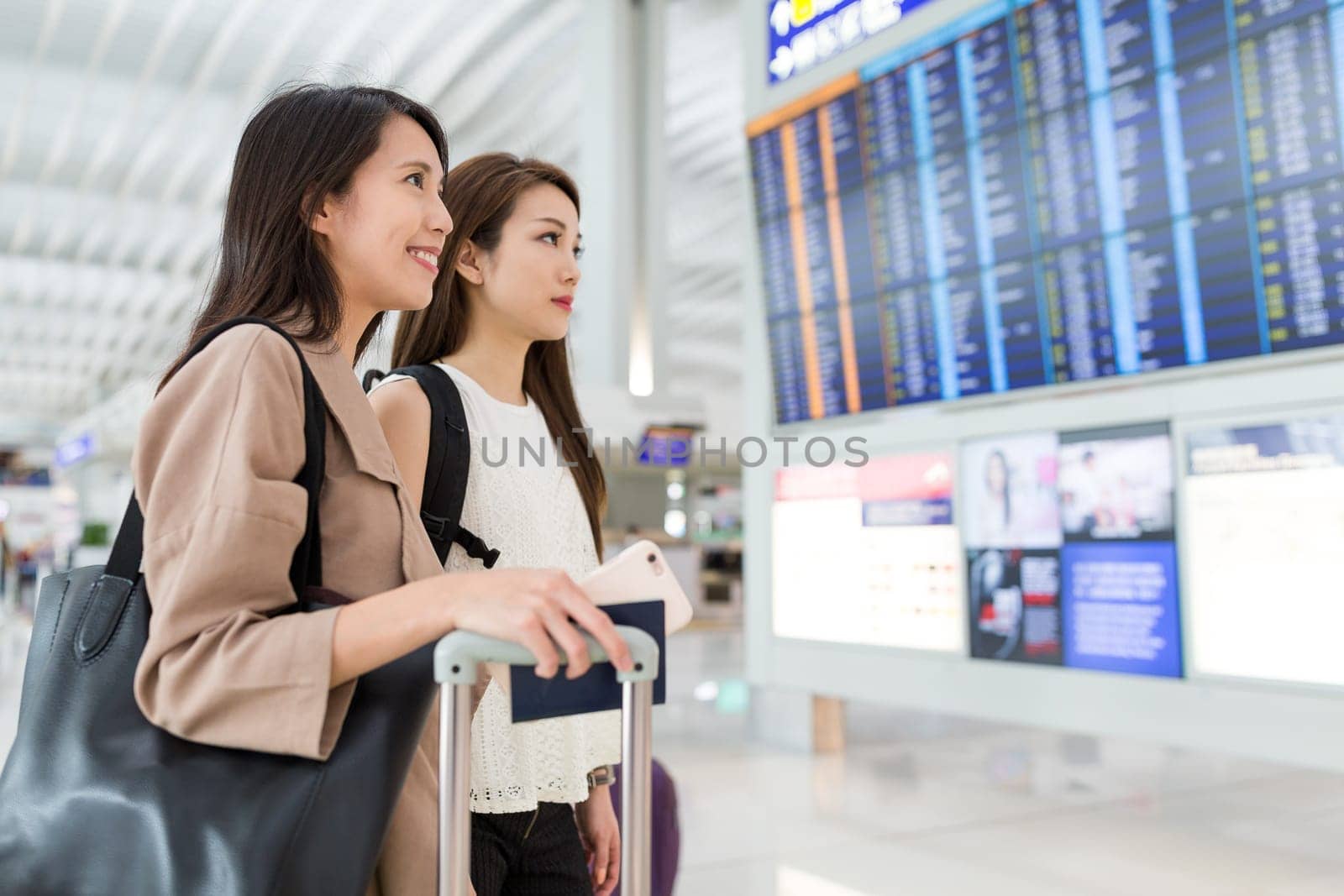 Women checking flight number together in airport