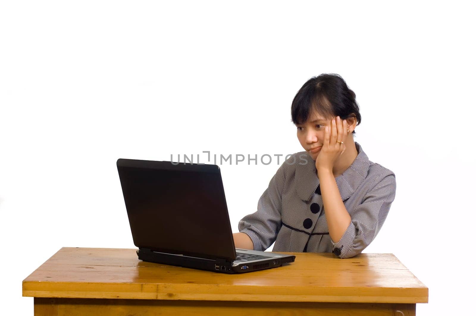 Beautiful asian business woman looking serious at her laptop on white background