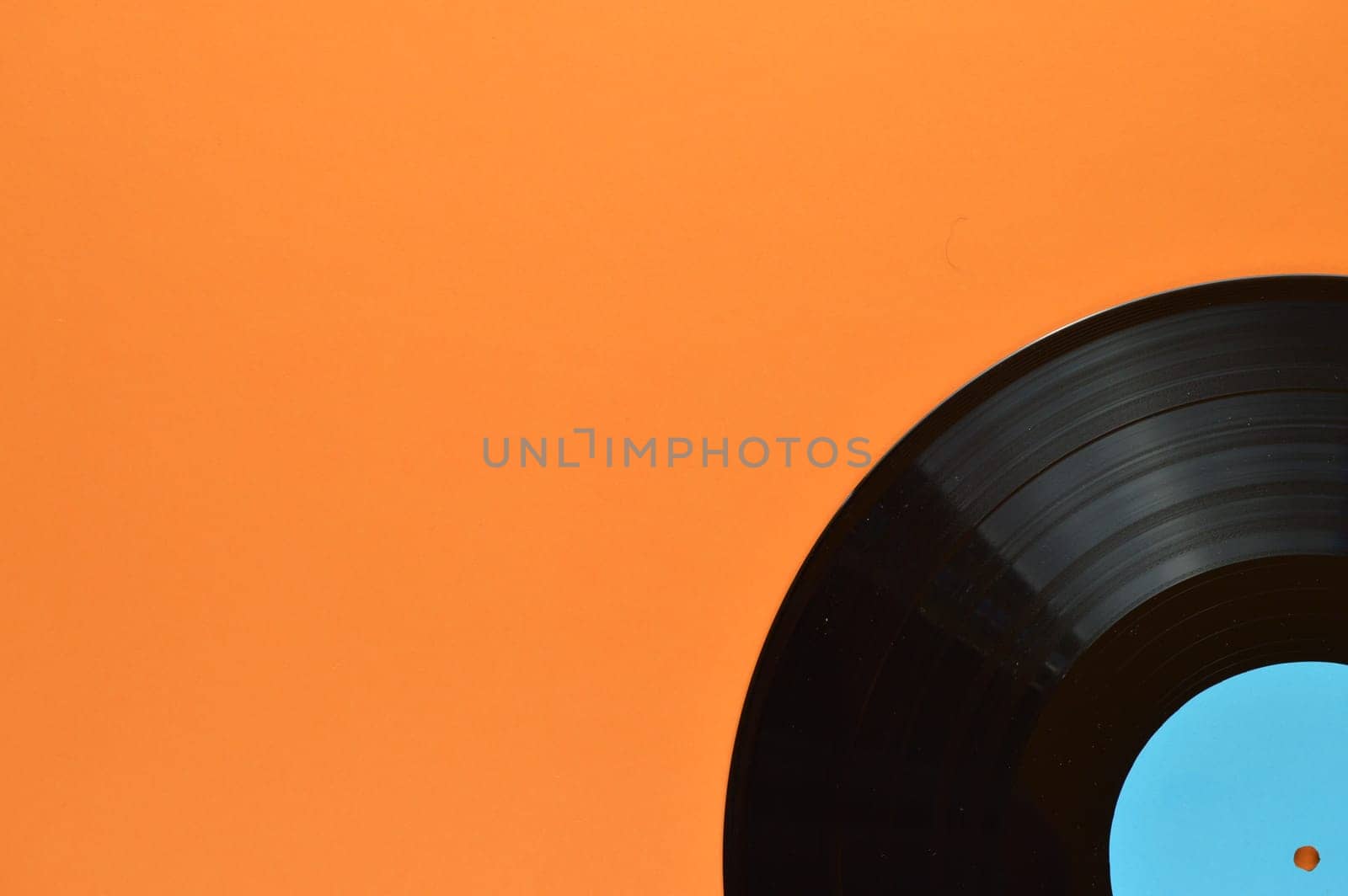 old black vinyl record with blank cyan label in the edge of orange background