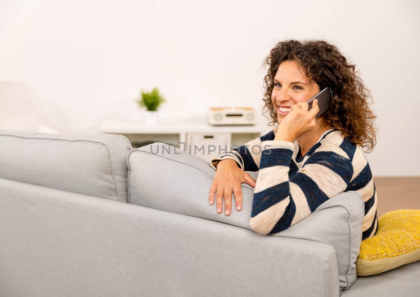 Beautiful woman sitting on the sofa and making a phone call