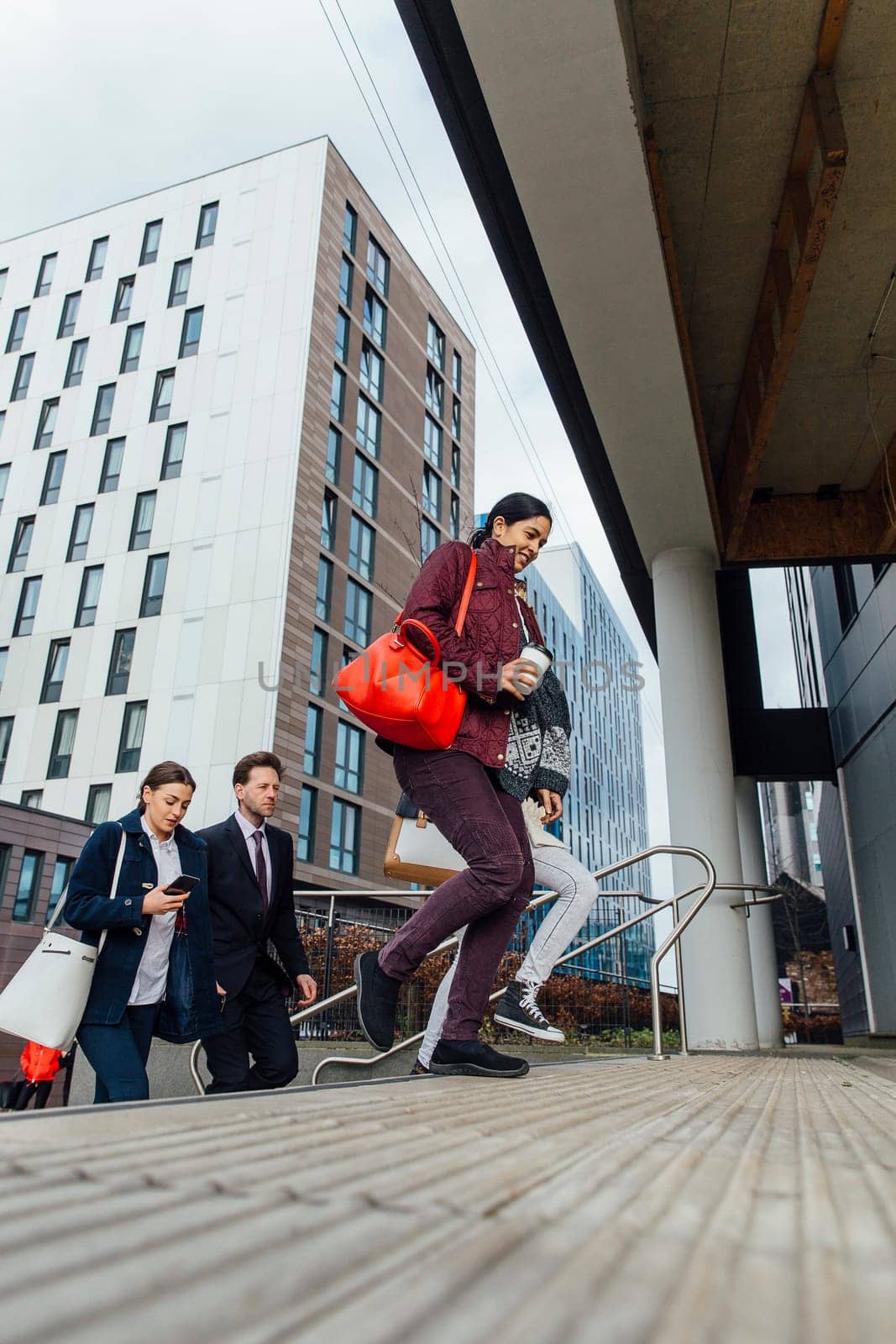 Group of people are walking up the entrance to their corporate office building in the city.