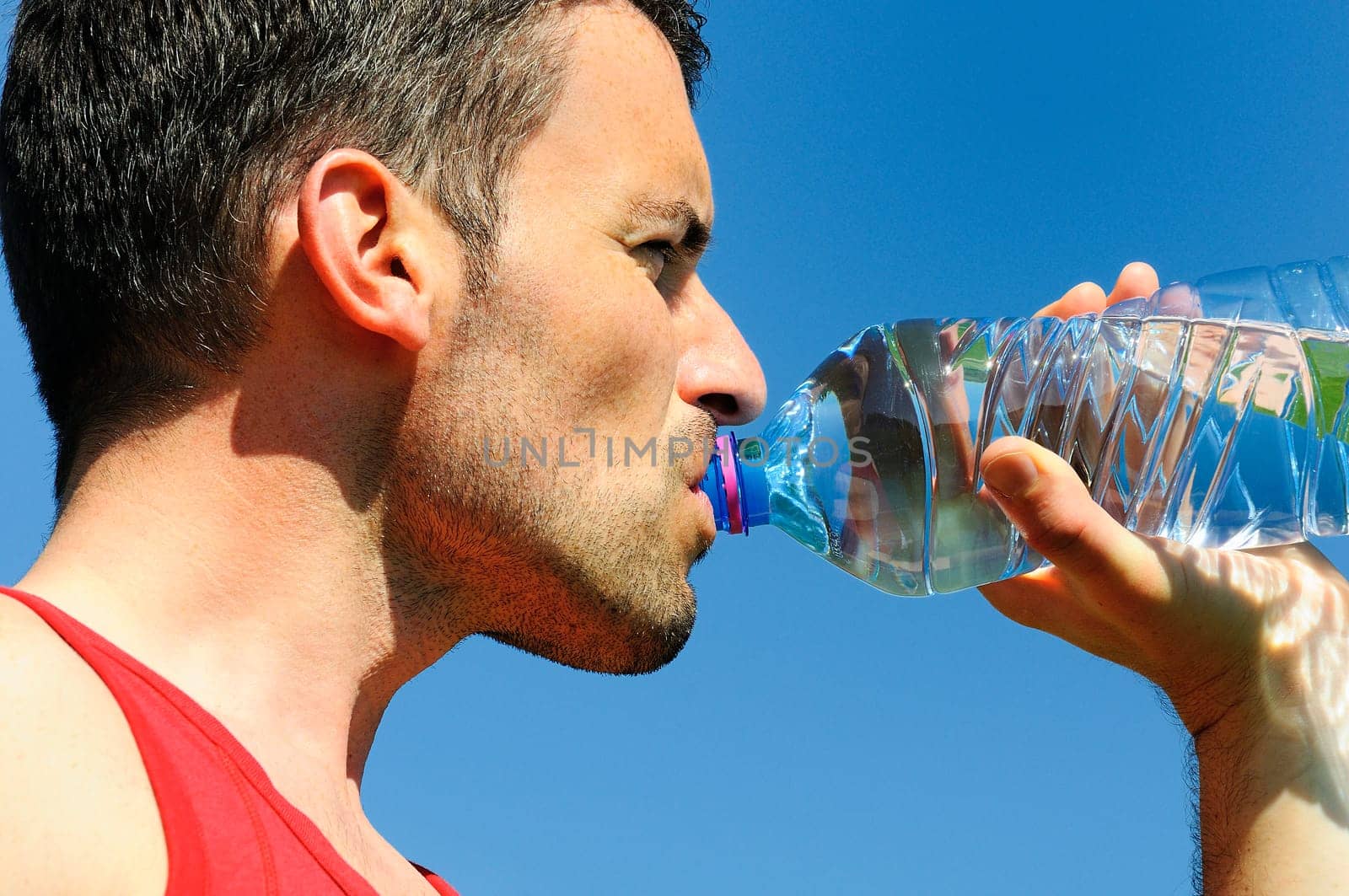 Man is drinking water against blue sky