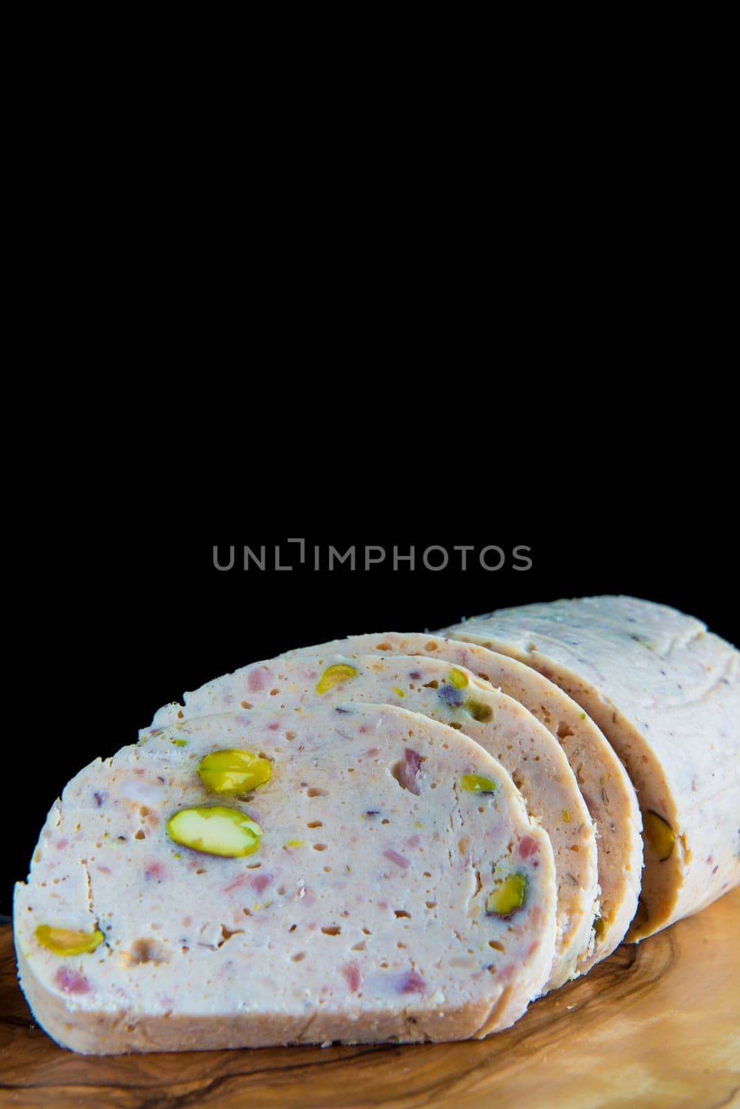 Cold meat made of chicken, bacon and pistachios sliced on a cutting board