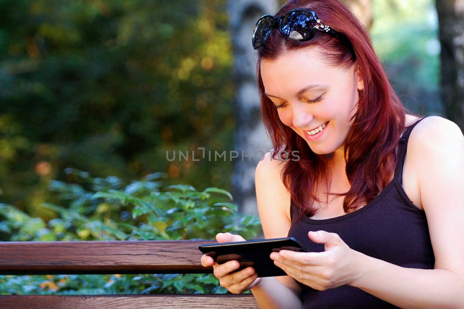 The woman is using tablet in the park.