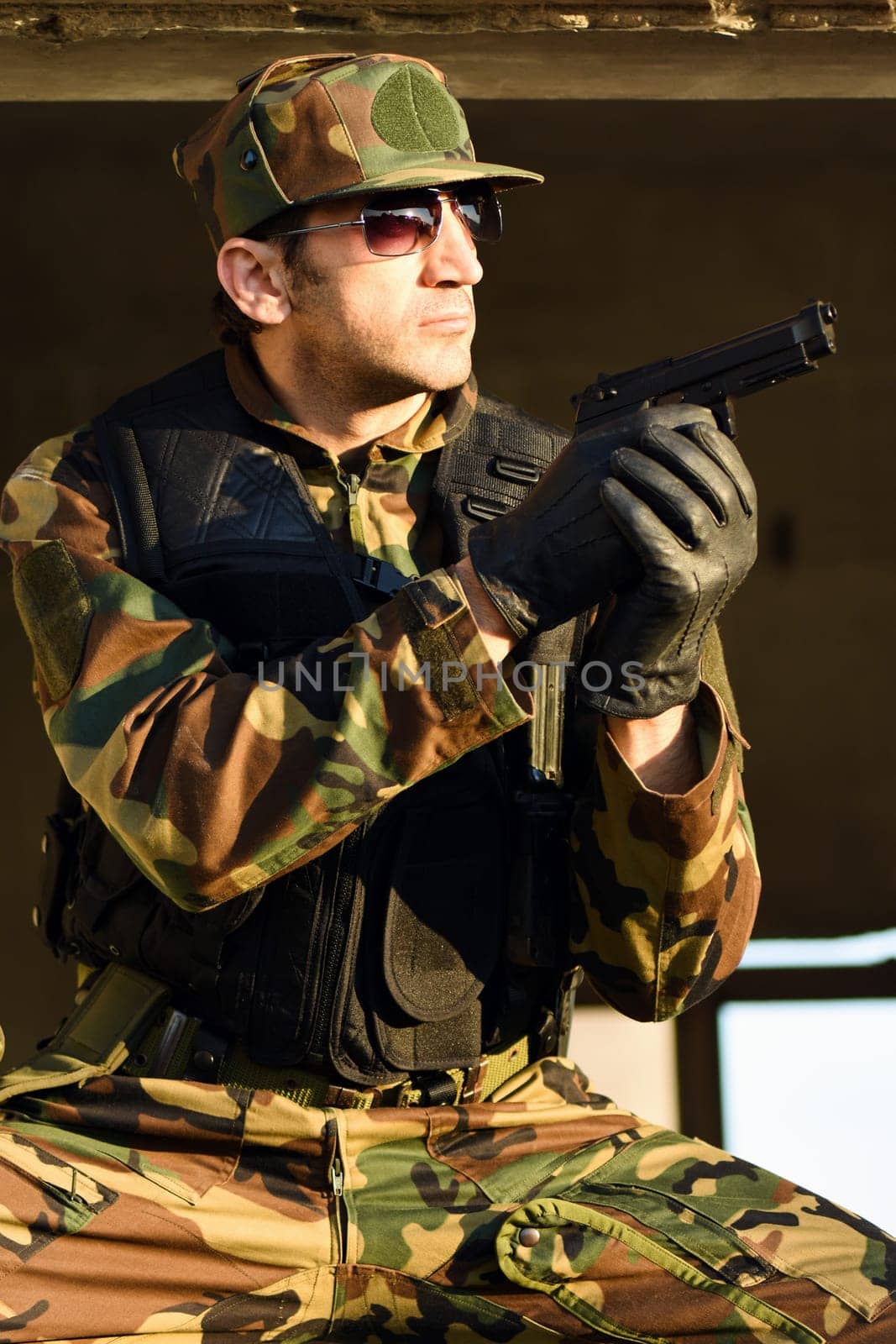The soldier in uniform is holding a handgun.