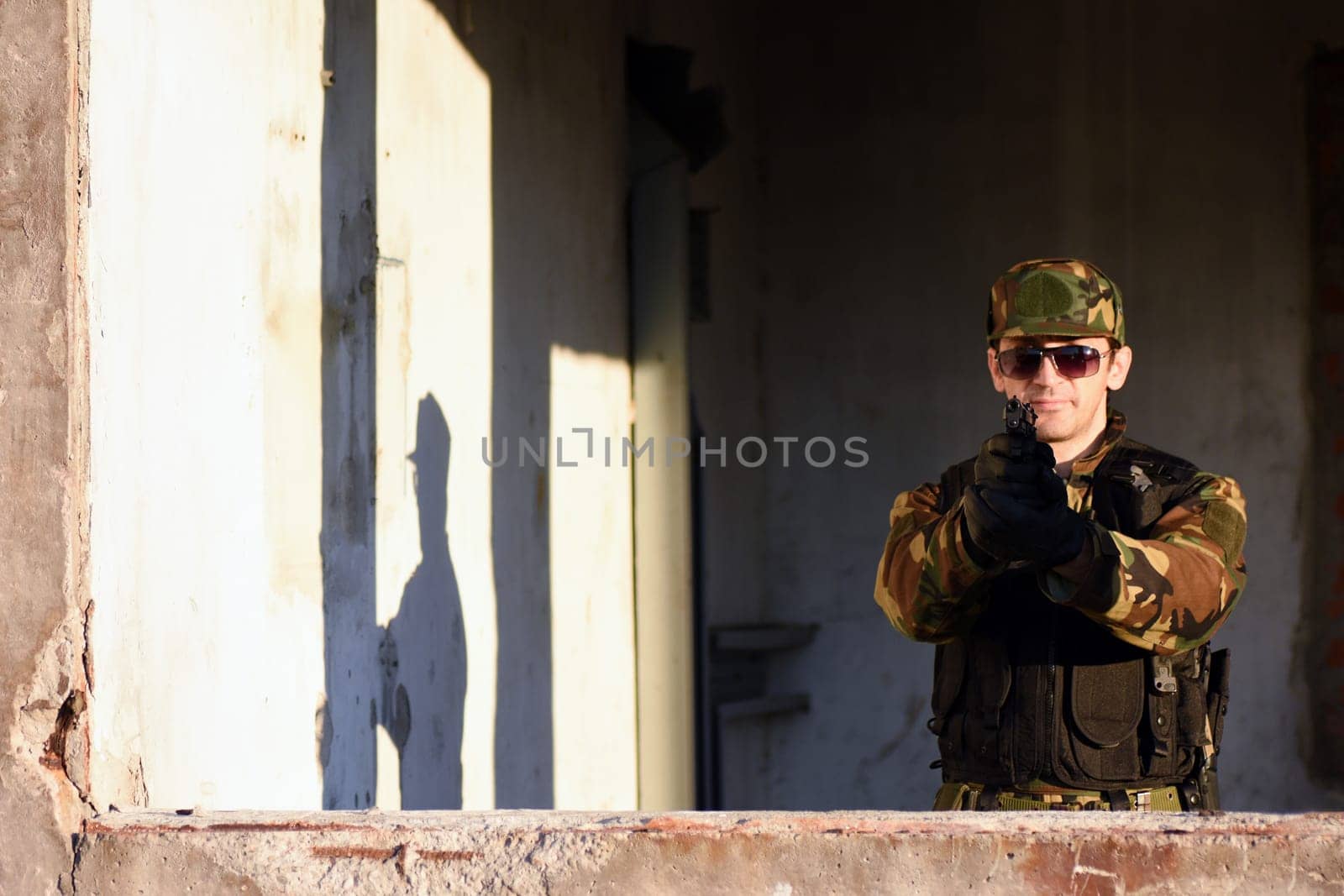The soldier is shooting with the gun.