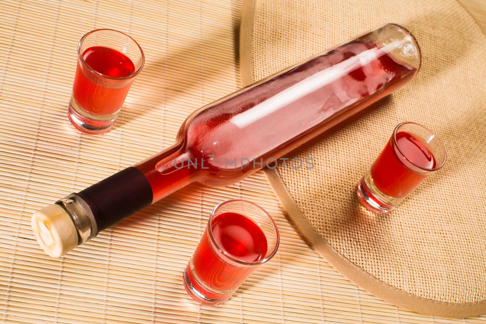 Alcohol bottle and glasses with red alcohol drink.