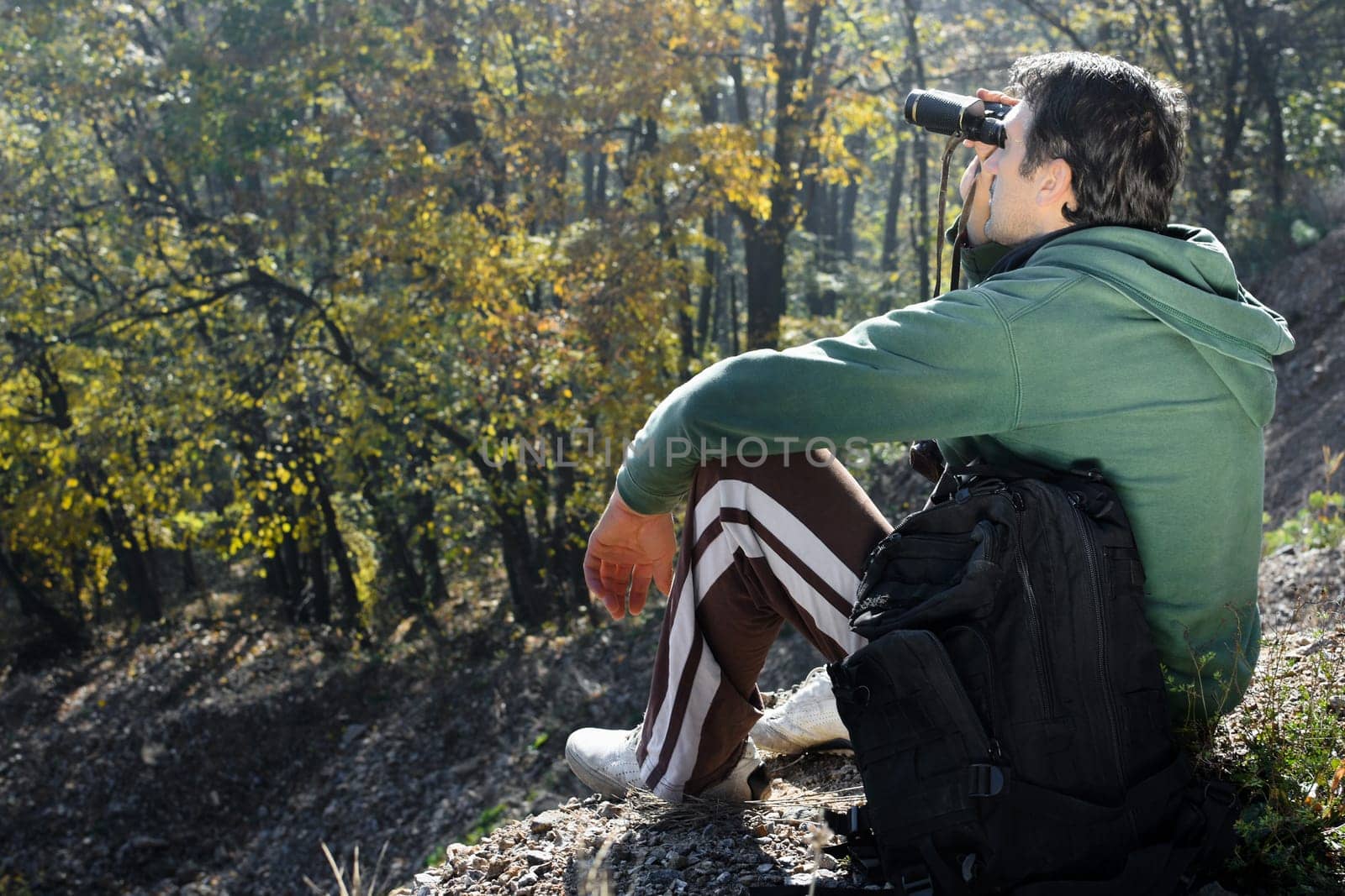 The mountaineer is looking away the nature with his binoculars.