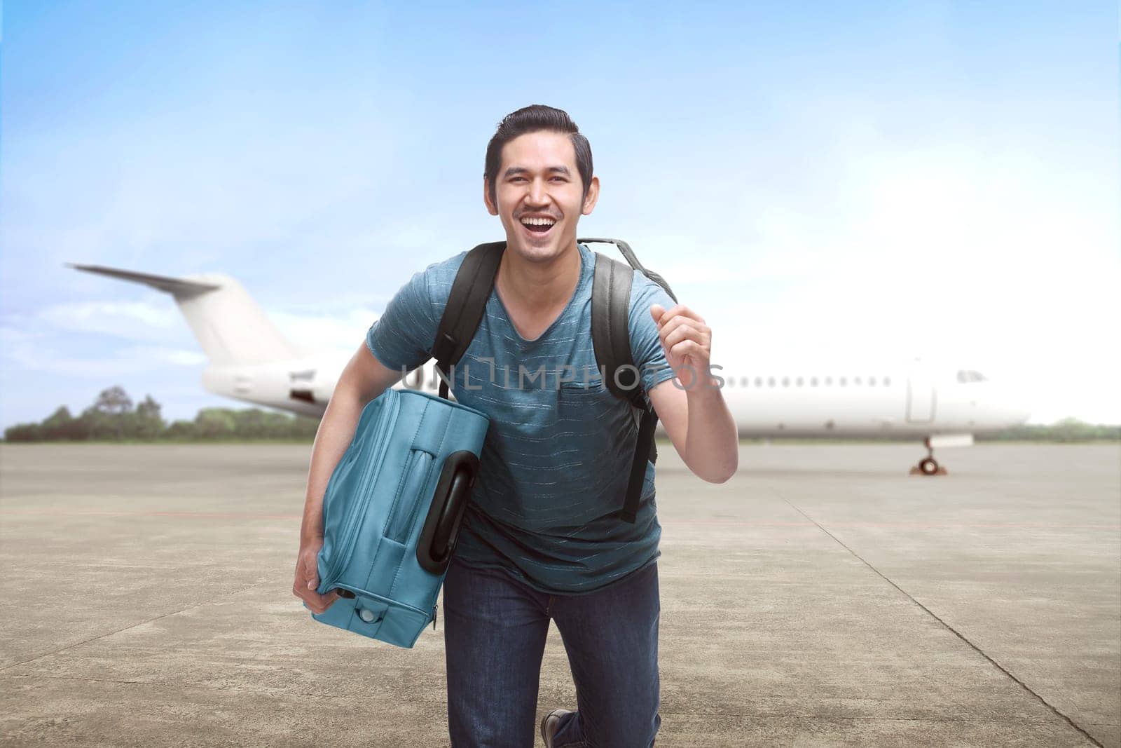 Young asian travelling man get off the plane with suitcase on the landing strip