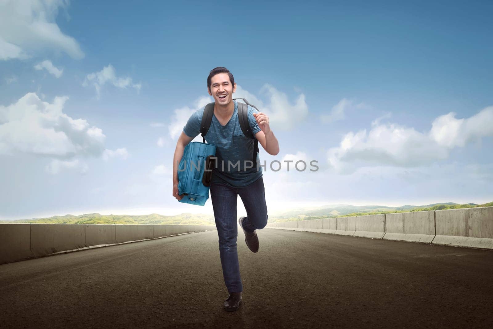 Happy asian tourist man carrying luggage running along the street