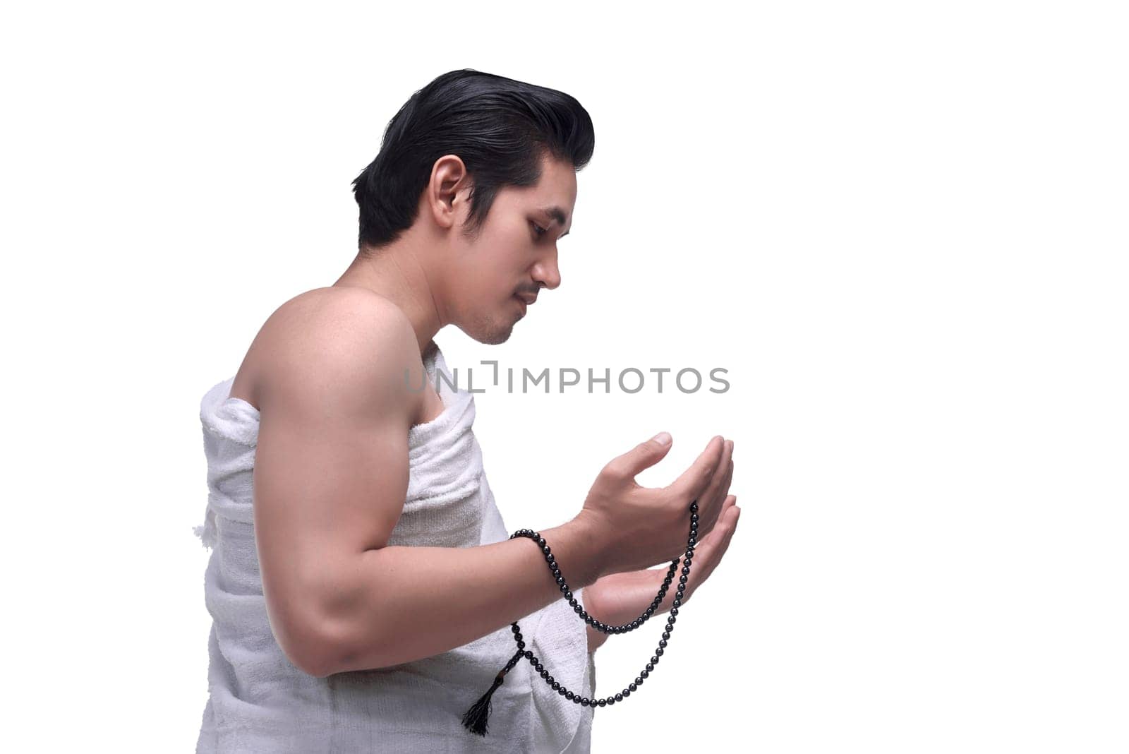 Side view of asian muslim man wearing ihram cloth praying isolated over white background