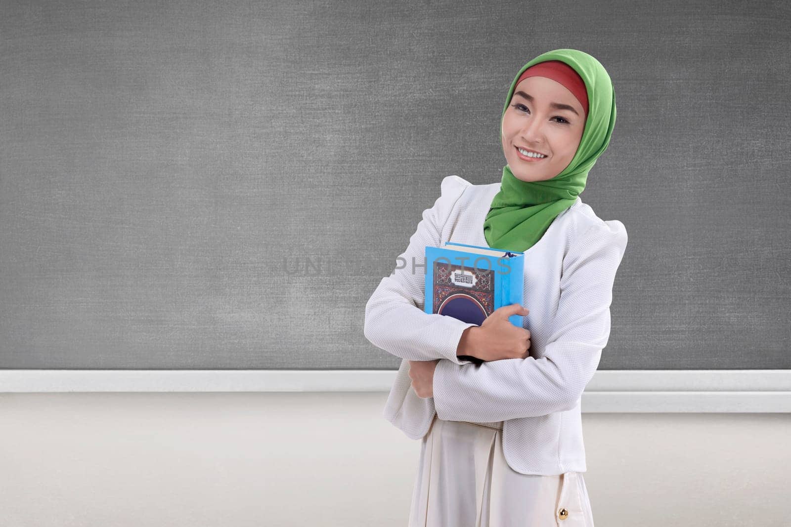 Pretty asian muslim woman holding the holy book Koran with blackboard background