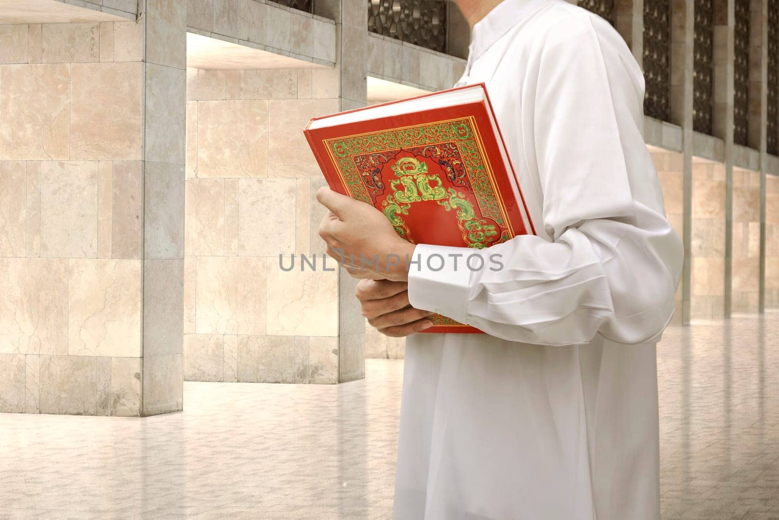 Muslim man holding the holy book Koran on the mosque