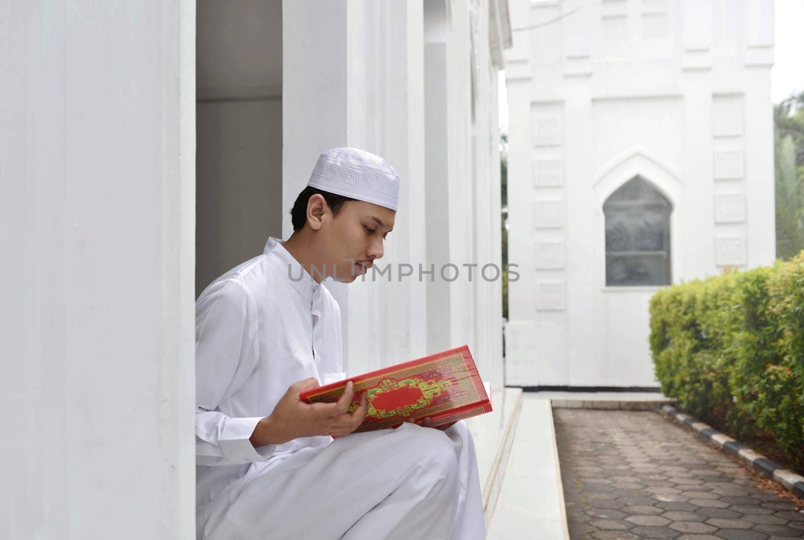 Young asian muslim man reading the holy book Quran in the mosque