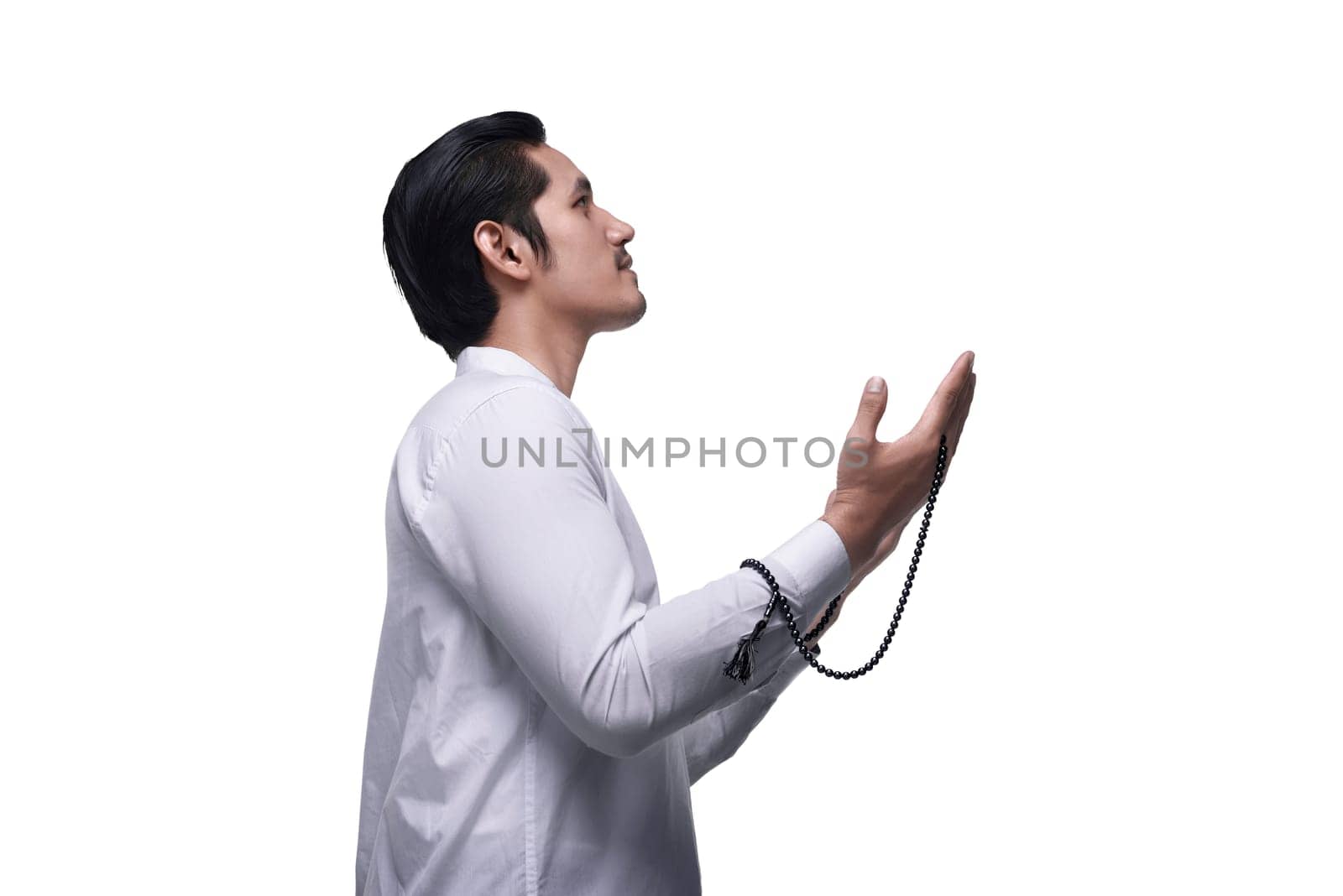 Side view of asian muslim man praying with prayer beads isolated over white background