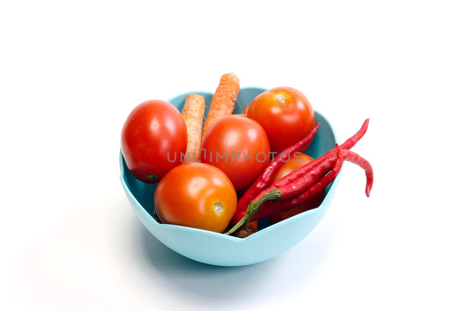 Tomatoes, Carrots, and Chilies in the blue basket on white background. Look tasty and fresh