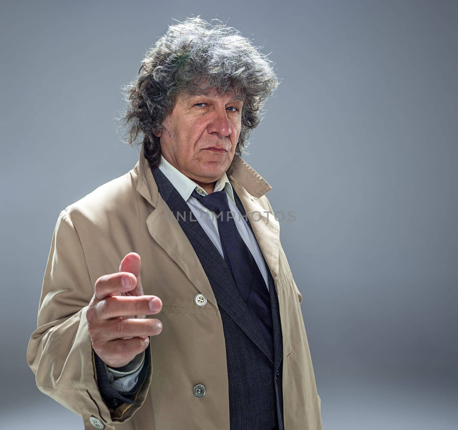 The senior man in cloak as detective or mafia boss. Studio shot on gray in retro stile