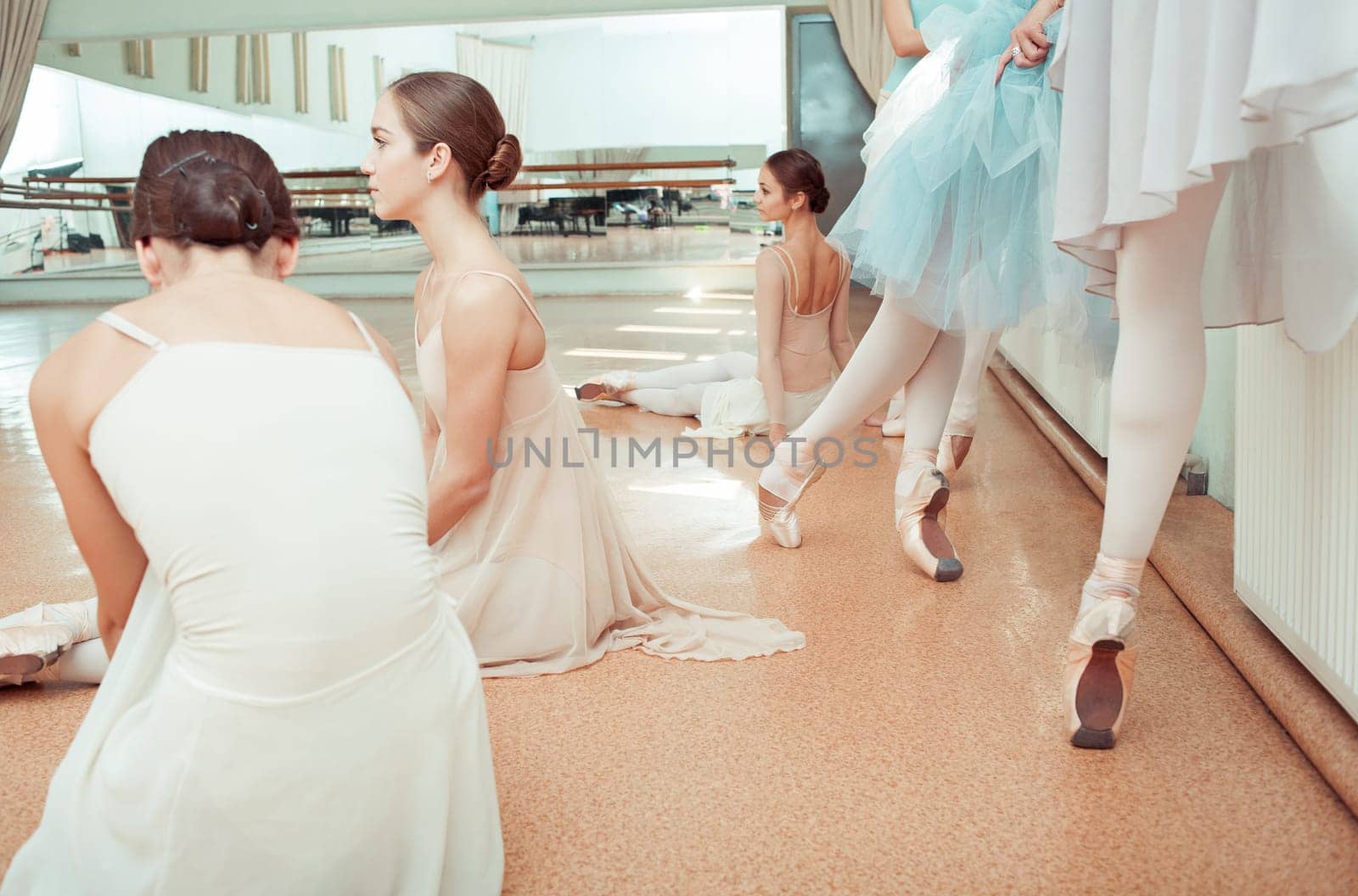 Thr seven ballerinas at ballet rack in the rehearsal hall of the theater