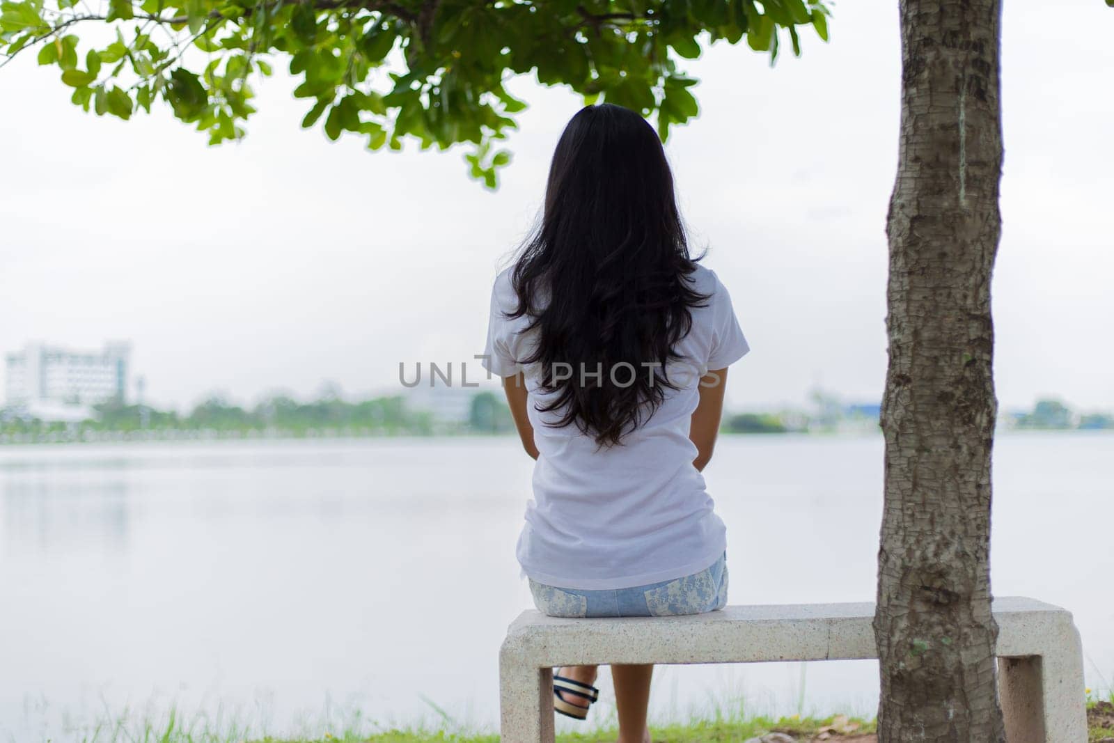 Asian woman is sitting on the rock in the park