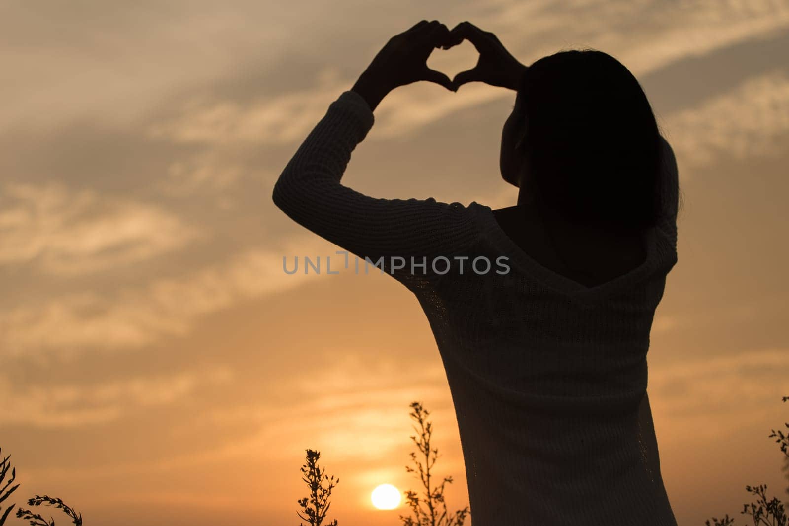 Silhouette of a young asian woman enjoying flowers and nature sunset