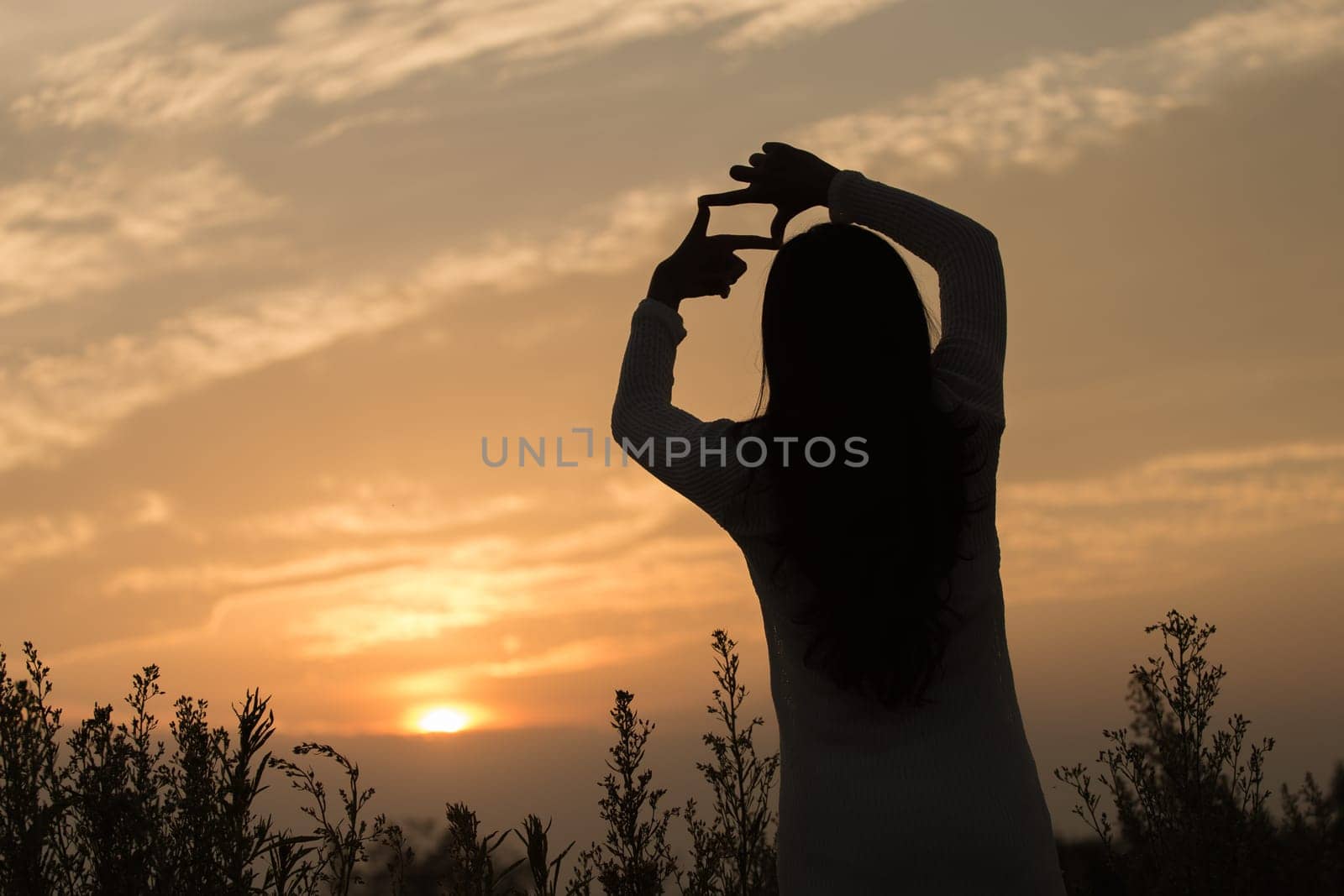 Silhouette of a young asian woman enjoying flowers and nature sunset