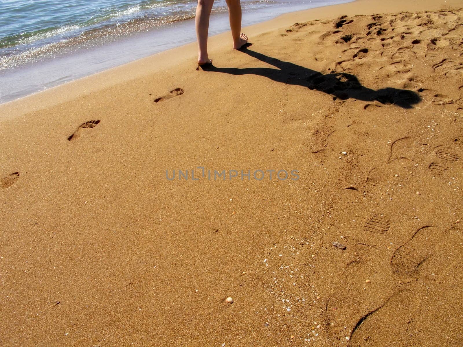 close up young adult woman walking on sandy beach