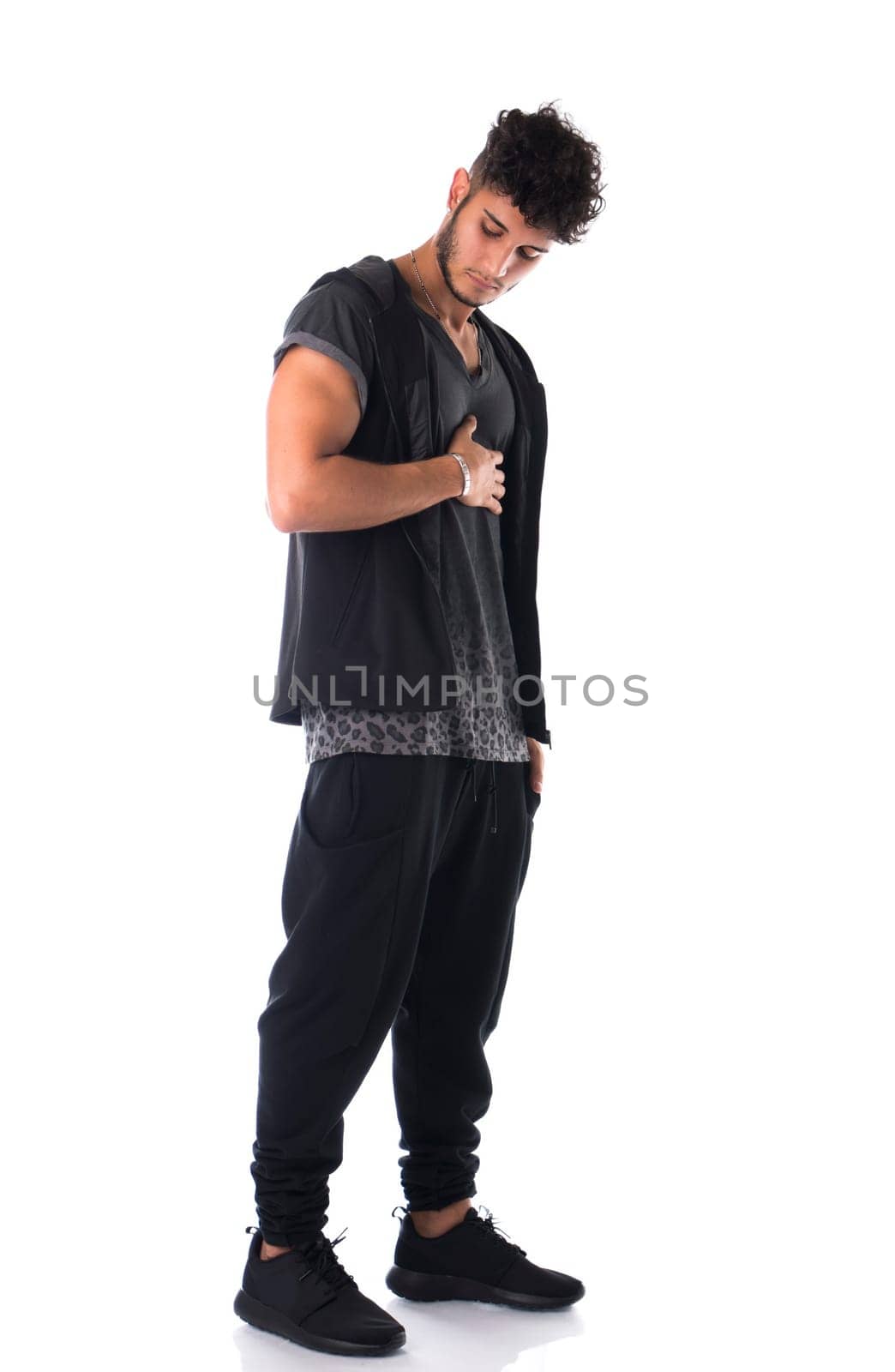 Full length shot of handsome tough young man in dark t-shirt isolated on white background, looking down