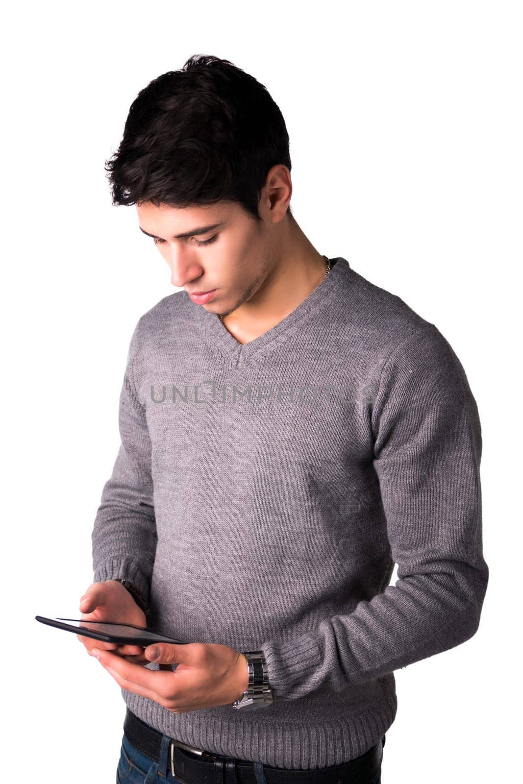 Handsome young man holding ebook reader and reading text on it, standing isolated on white background