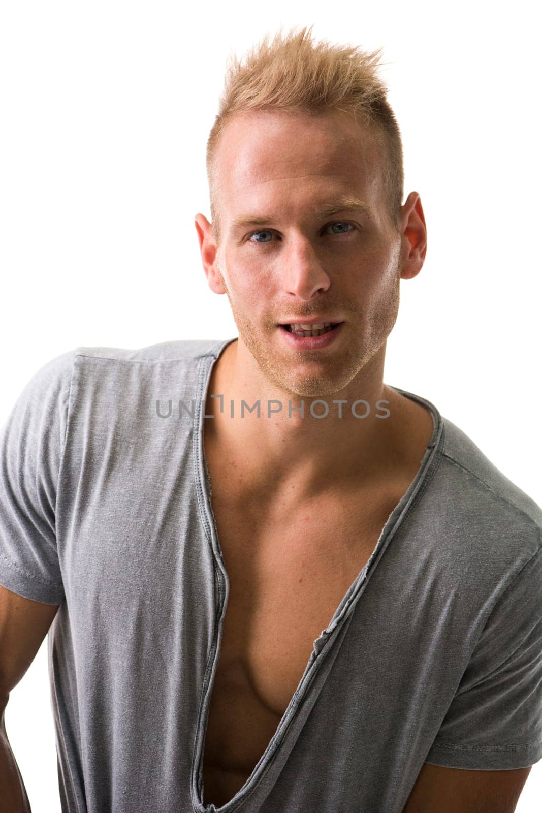 Fit male model smiling with a lot of confidence wearing grey t-shirt revealing muscular chest, looking at camera
