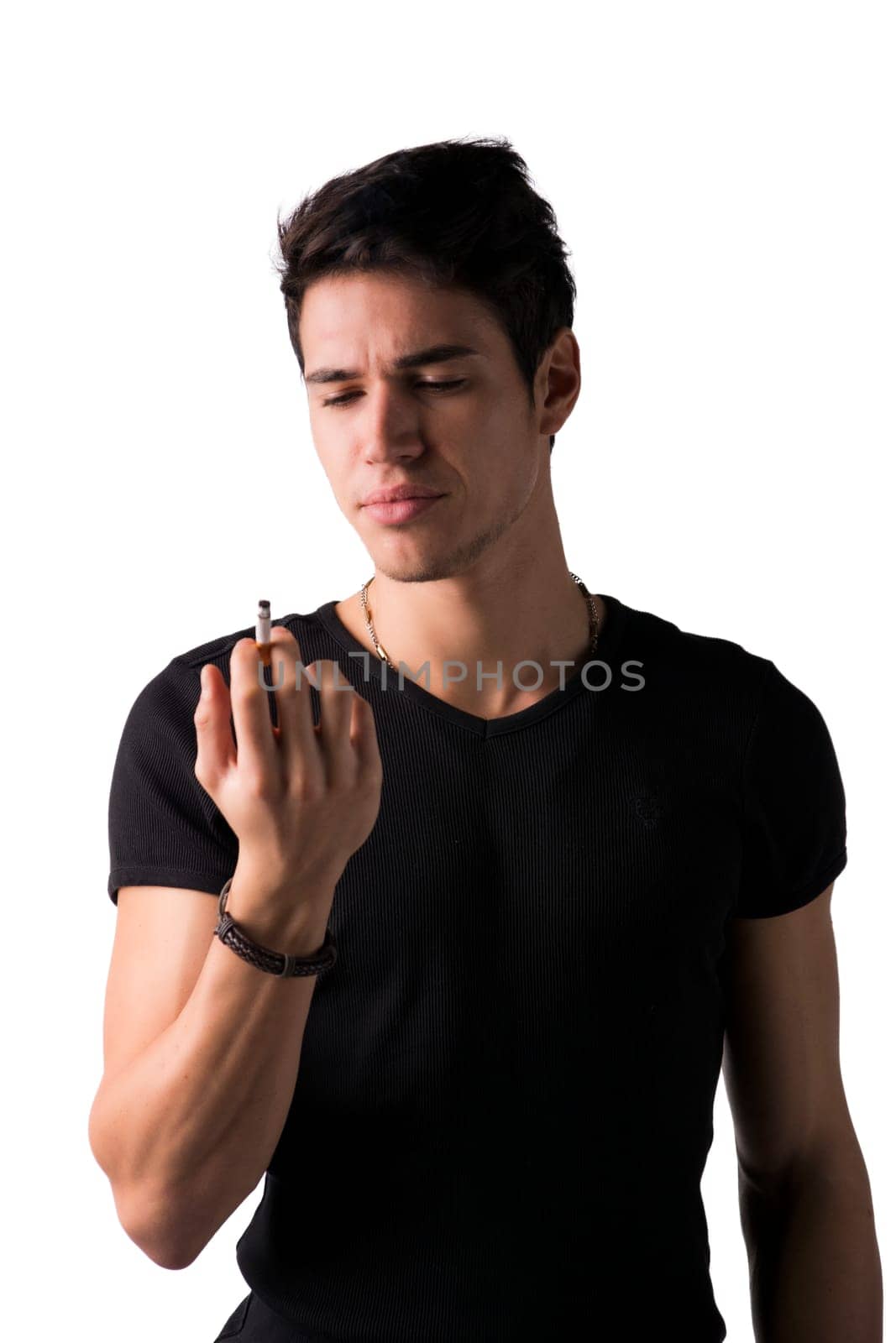 Young man disgusted by cigarette he's holding in his hand. Standing isolated on white background looking at it