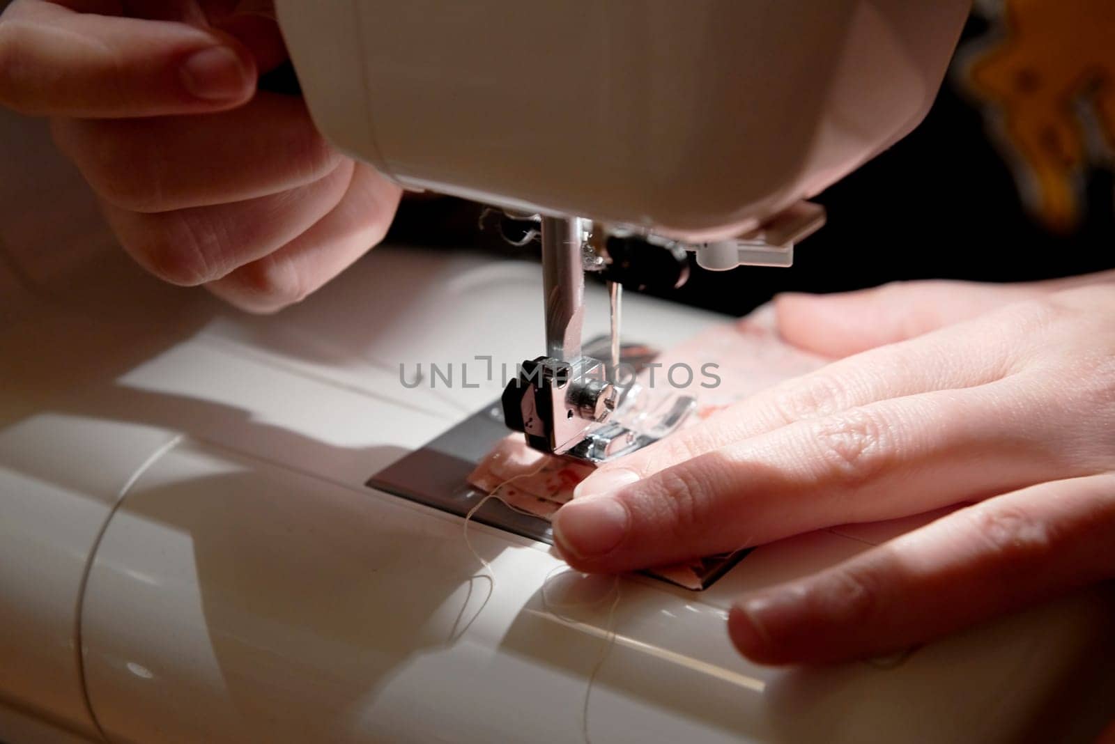 Detail of hands working on piece of fabric on automatic sewing machine