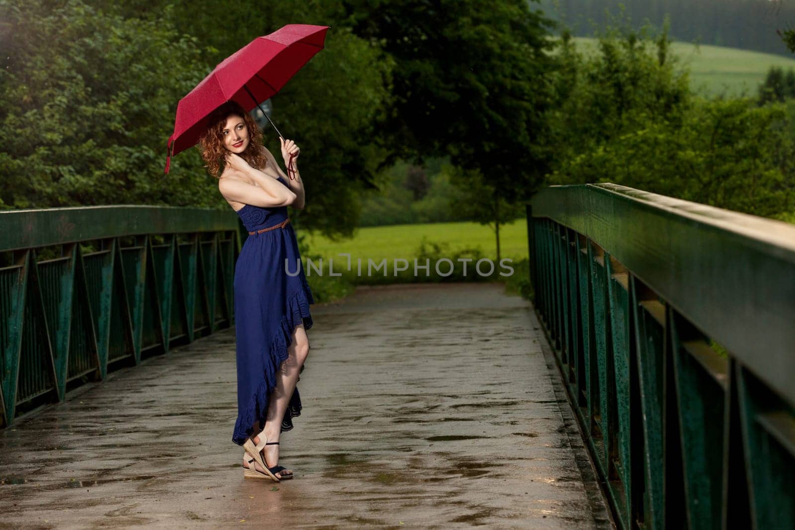 Young attractive woman with red umbrella after rain in nature
