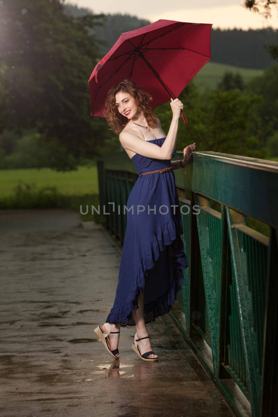 Young attractive woman with red umbrella after rain in nature
