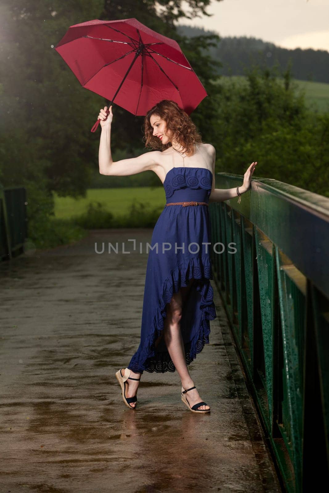 Young attractive woman with red umbrella after rain in nature