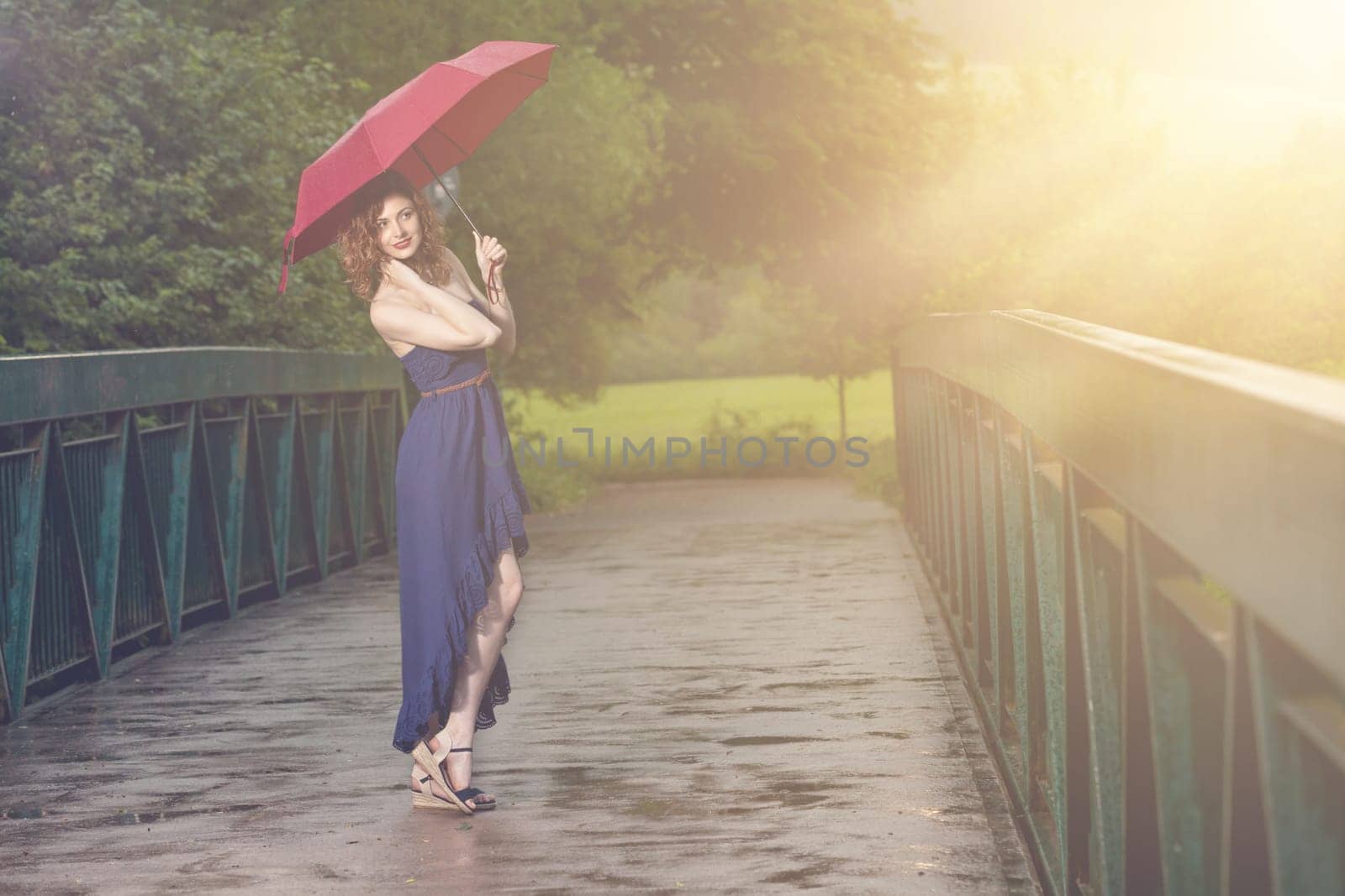 Young attractive woman with red umbrella after rain in nature