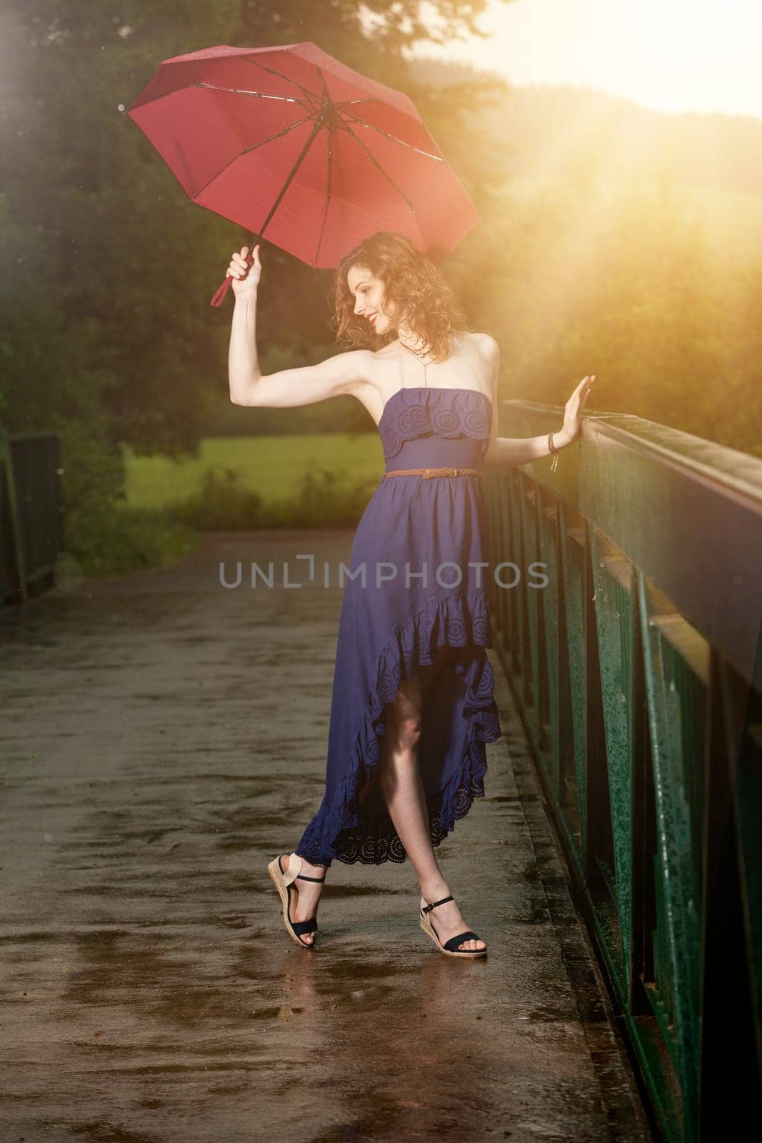 Young attractive woman with red umbrella after rain in nature
