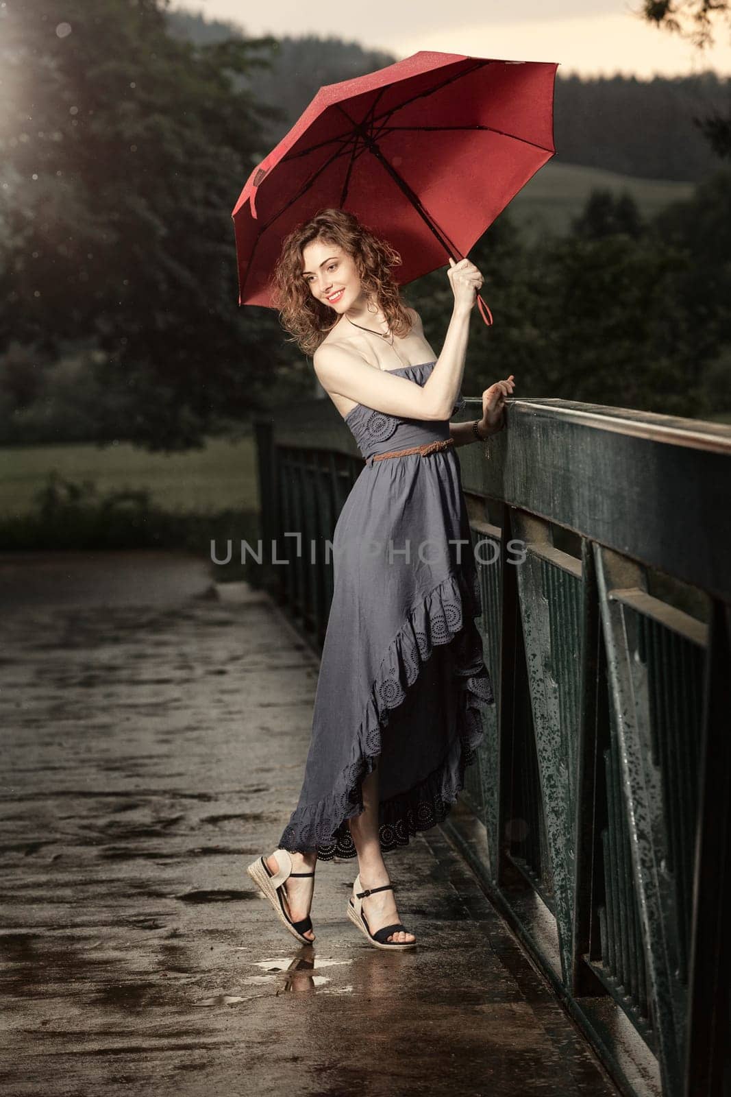 Young attractive woman with red umbrella after rain in nature