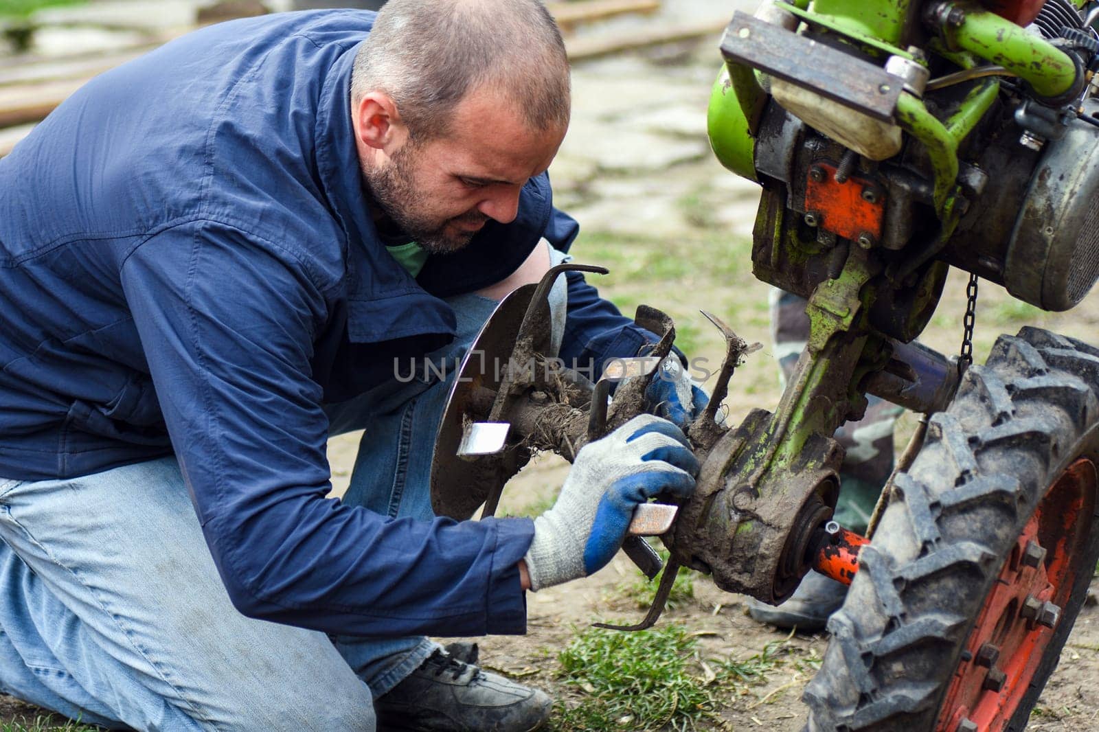 The worker is repairing the agricultural machine.