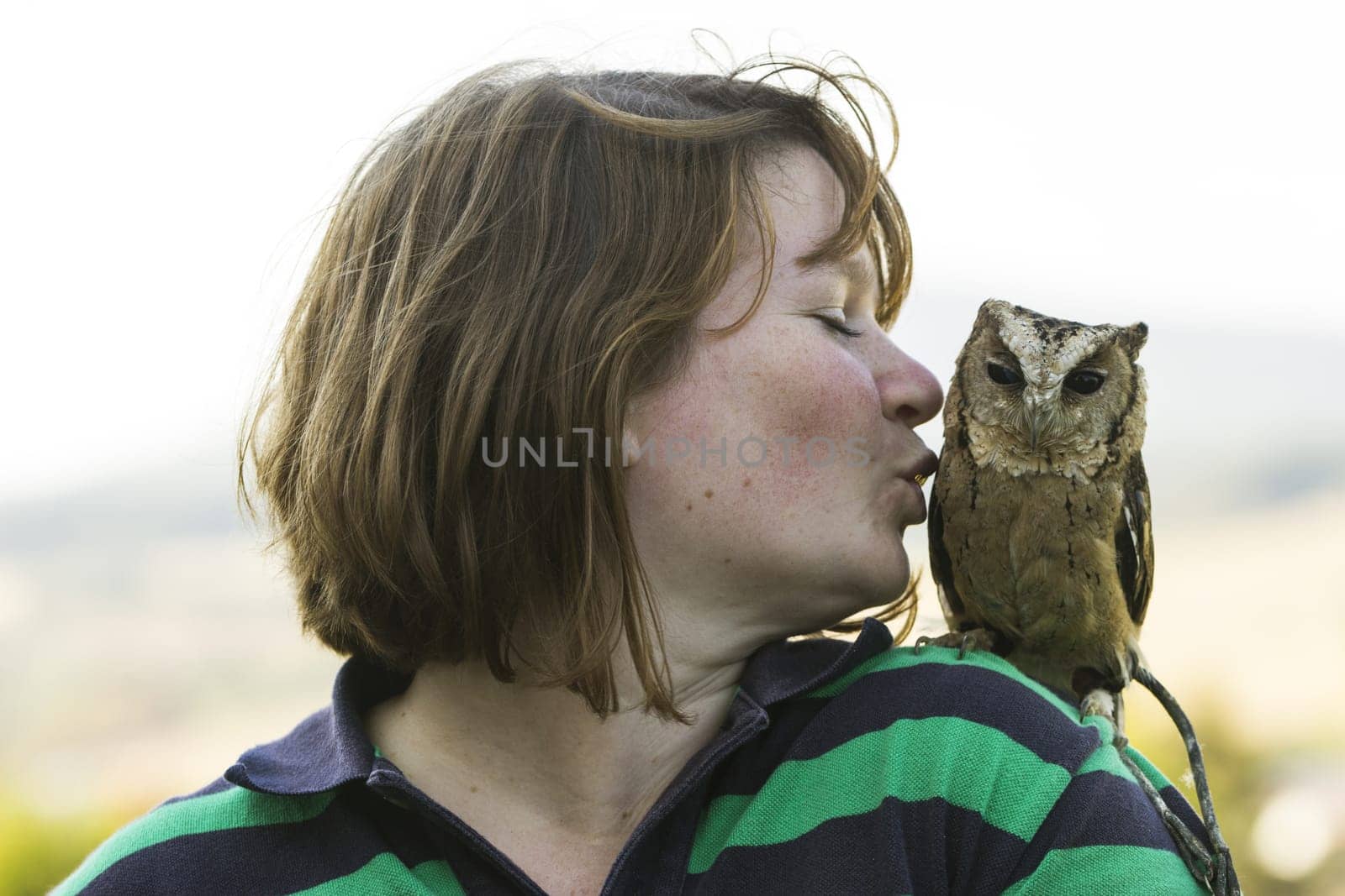 Young woman with Hindu collared owl on shoulder