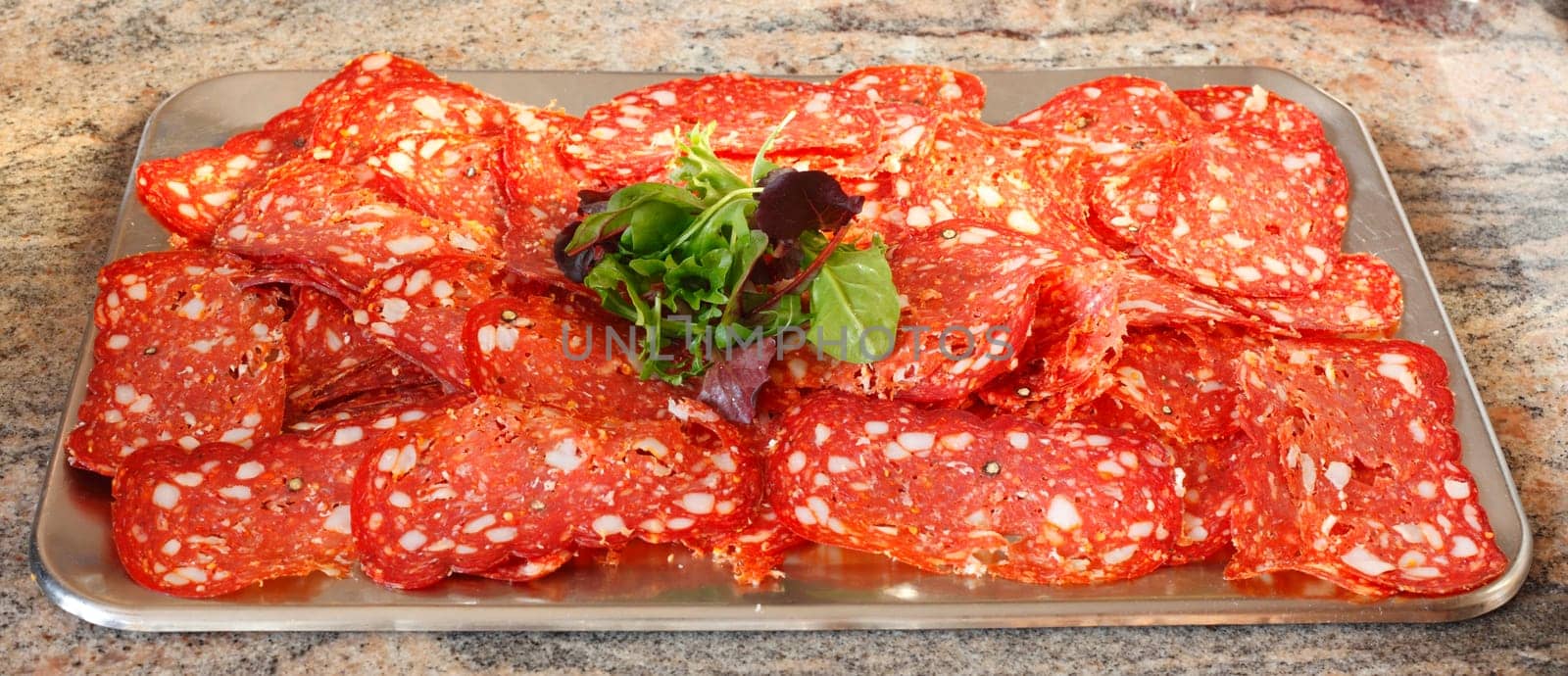 Plate topped with salami and salad