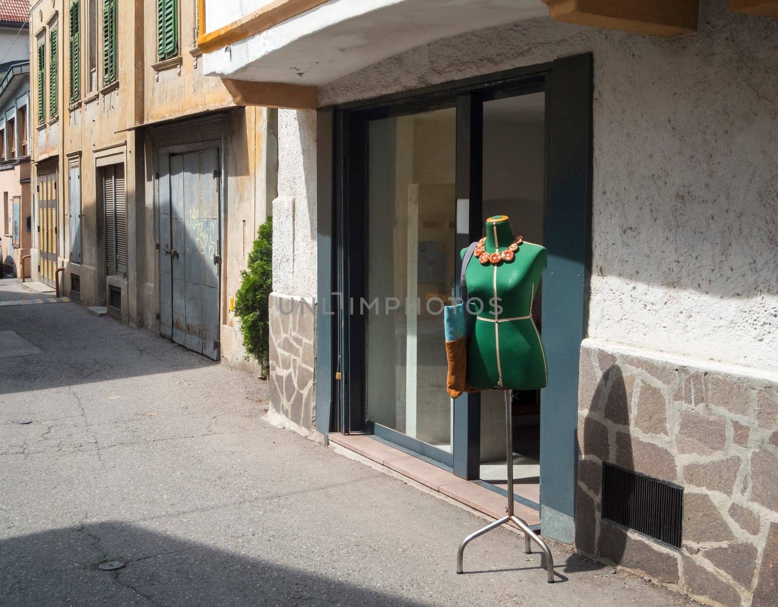 Green tailor doll in front of shop window in a small alley in Merano / South Tyrol..