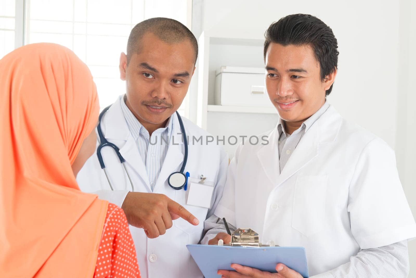 Medical doctor explaining health result to patient. Southeast Asian Muslim people.