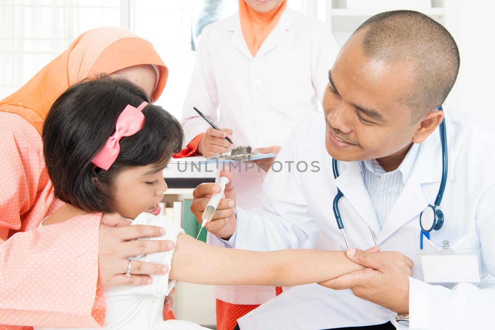 Southeast Asian doctor pediatrician injecting vaccine to children. Muslim family.