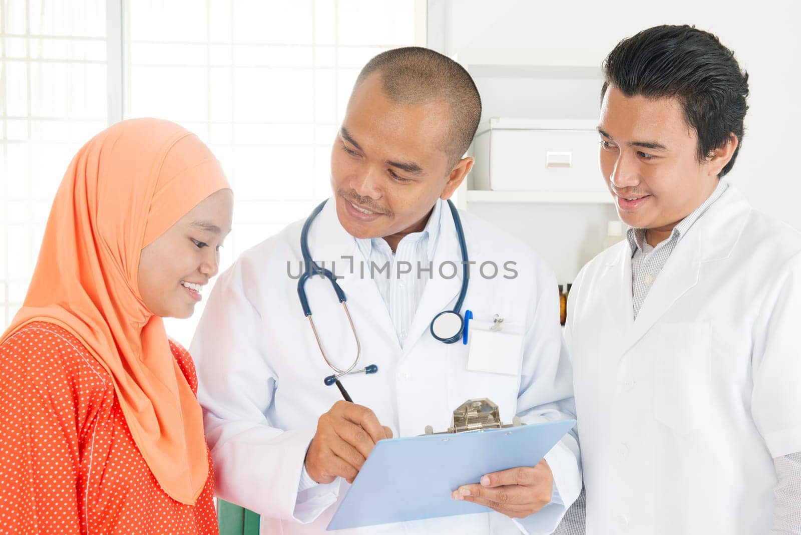 Medical team discussing treatment options with patients. Southeast Asian Muslim people.