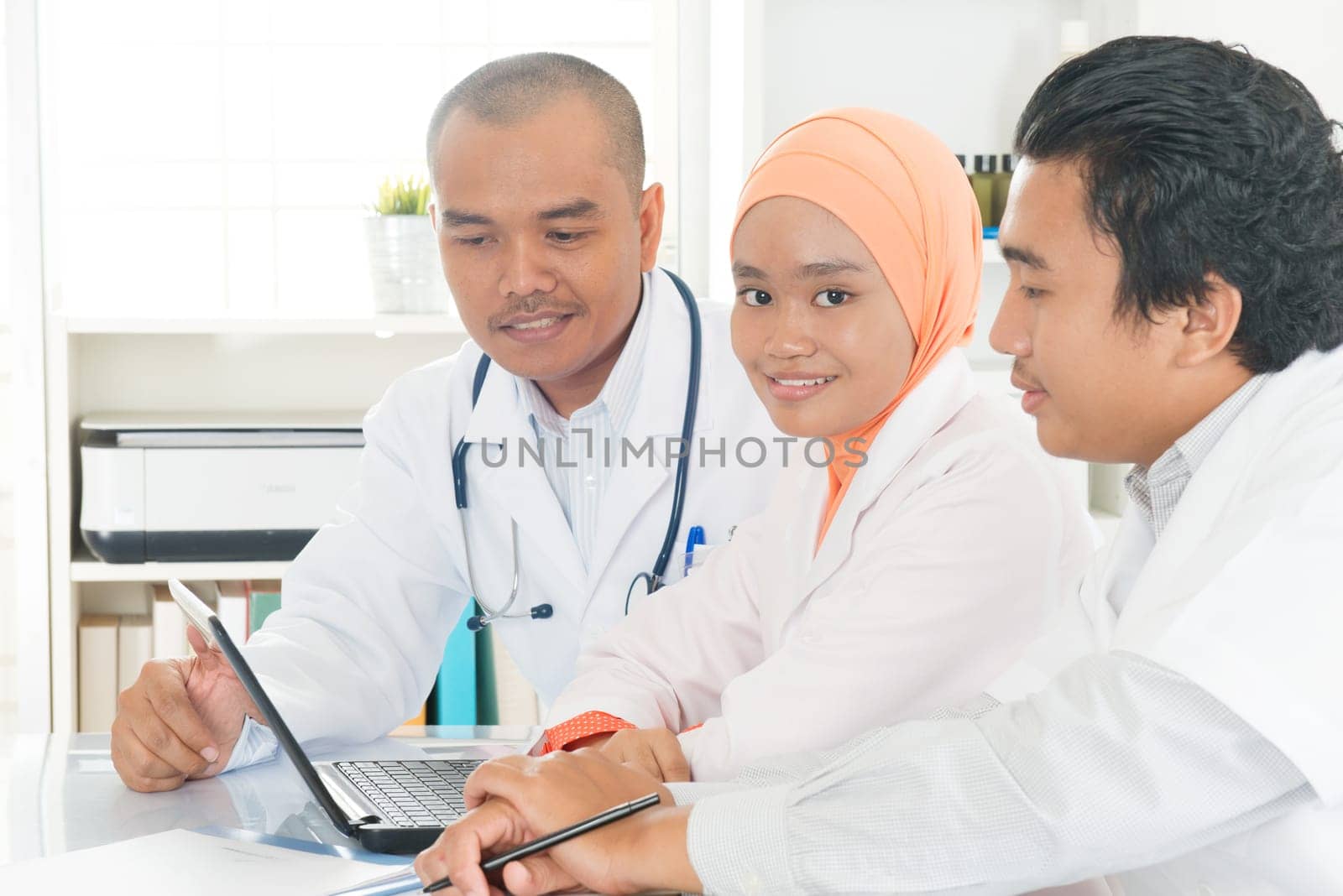 Medical team interacting at a meeting in conference room. Southeast Asian Muslim doctors and nurses.
